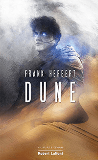 C'est la couverture de "Dune" écrit par Frank Herbert. On voit un personnage avec des yeux bleu lumineux, les cheveux noirs au vent et une dune.